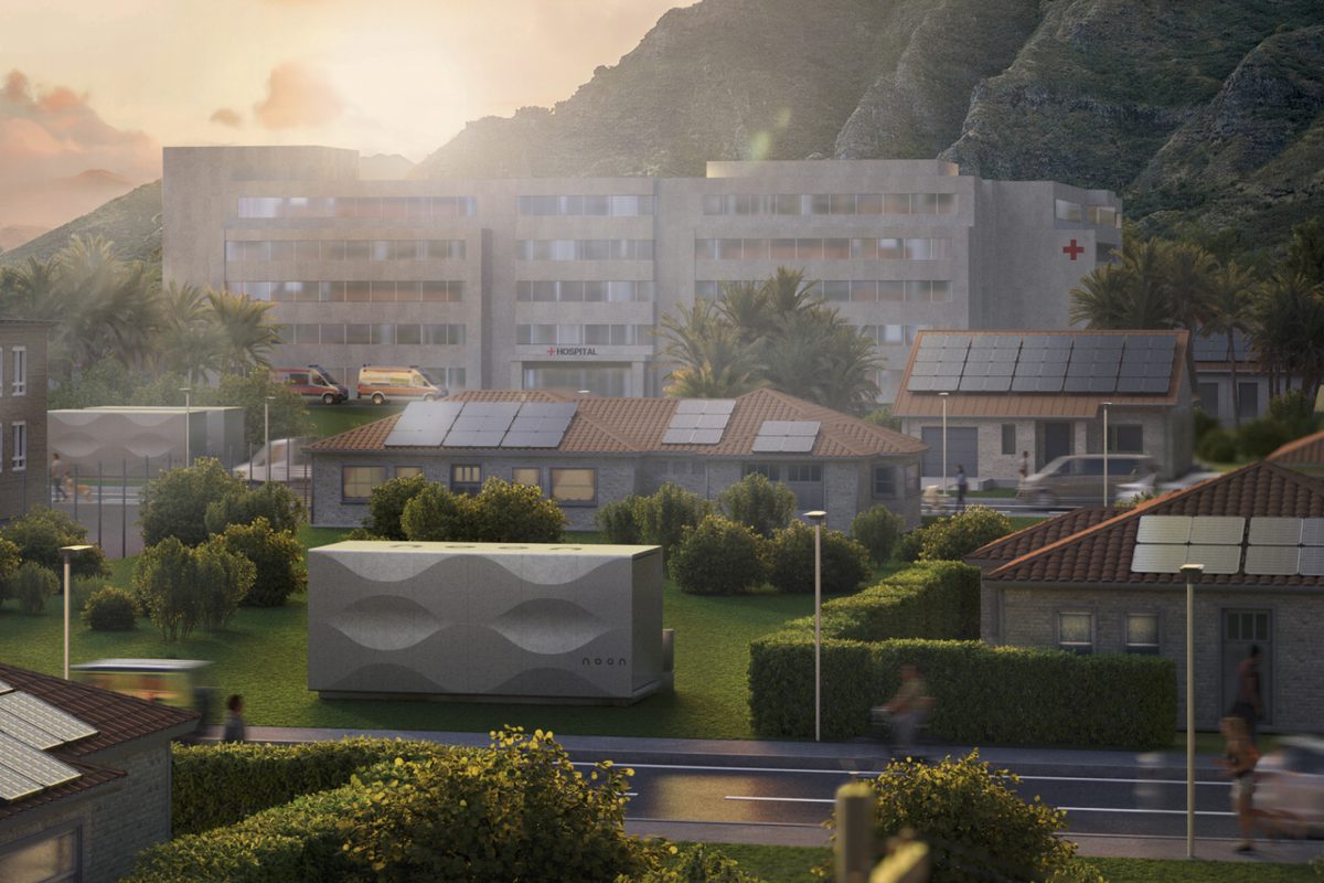 A large cubic noon battery with buildings in the back during sunset.